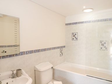 A bathroom with a sink a toilet and a bathtub with tiled walls at Emminster in Nottington near Weymouth