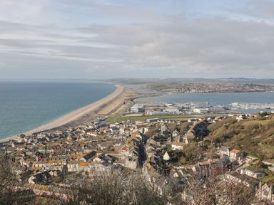 A coastal town with houses hills and a long stretch of beach at Emminster in Nottington near Weymouth