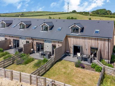 A row of modern townhouses with wooden and stone exteriors and small fenced gardens at Durbyfield in Nottington near Weymouth
