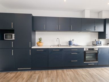 A kitchen with dark cabinets and appliances at Durbyfield Nottington near Weymouth