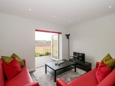 A living room with two red sofas cushions coffee table tv and floor lamp at Egdon Heath in Nottington near Weymouth