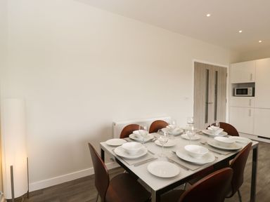 A dining table set with plates bowls glasses and cutlery surrounded by brown chairs in a dining area at Egdon Heath in Nottington near Weymouth