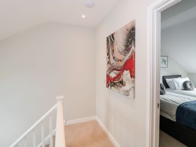 A hallway with a painting on the wall and a view of a bedroom with a bed and pillows at Egdon Heath in Nottington near Weymouth