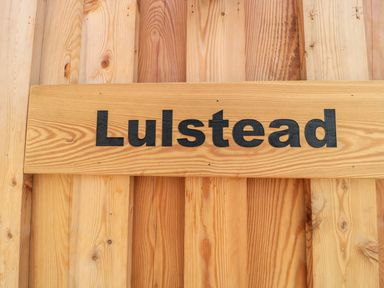 A wooden sign with the word Lulstead on a wooden plank background at Lulstead in Nottington near Weymouth