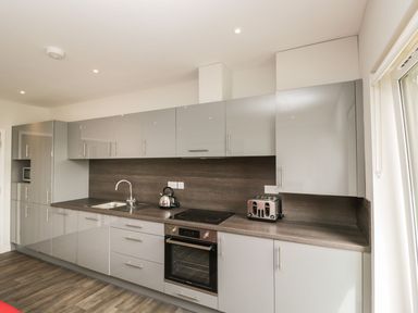 A kitchen with grey cabinets a sink a kettle a toaster an oven and a window at Lulstead in Nottington near Weymouth