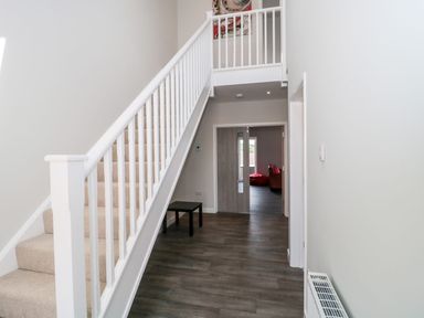 A hallway with a staircase and a small table near the wall at Lulstead in Nottington near Weymouth