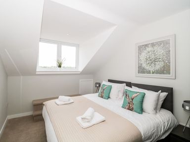 A bedroom with a double bed with two bunny cushions near a window with a plant on the sill at Lulstead in Nottington near Weymouth