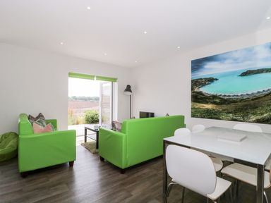 A sitting room with green sofas a dining table and a large seascape photo on the wall at Overcombe Mill in Nottington near Weymouth