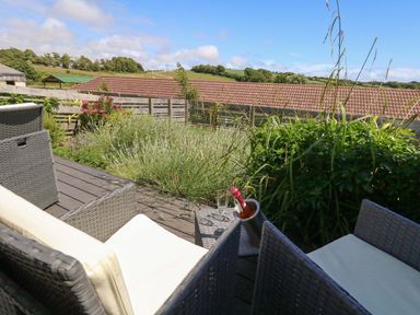 An outdoor area with seating and plants at Overcombe Mill in Nottington near Weymouth