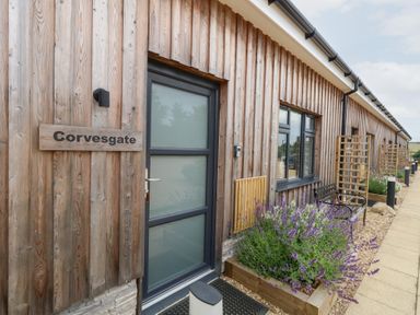 An outdoor entry area with a wooden exterior and a plant bed at Corvesgate in Nottington near Weymouth