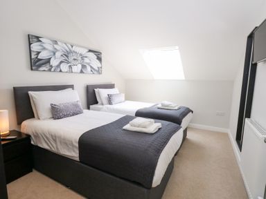 A bedroom with two beds and a window at Corvesgate in Nottington near Weymouth