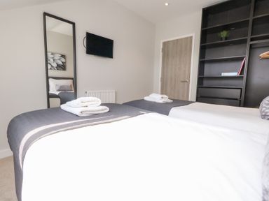 A bedroom with two beds and a television at Corvesgate Nottington near Weymouth