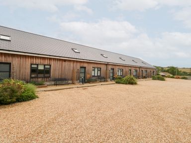 An outdoor view of a wooden building with gravel pathway at Corvesgate Nottington near Weymouth