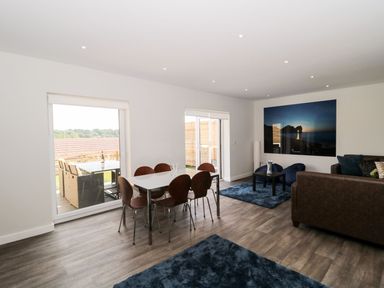 A living room with a dining table and chairs and sofas with blue rugs at Dirdale in Weymouth