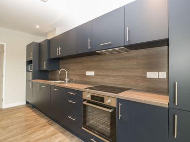 A kitchen with dark cabinets wooden countertop electric stove and oven at Dirdale in Weymouth