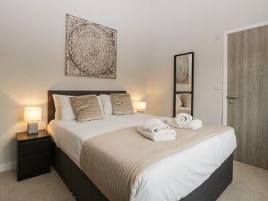 A bedroom with a bed with folded towels and bedside tables with lamps at Dirdale in Weymouth
