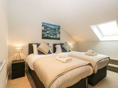 A bedroom with two single beds bedside tables lamps and a skylight window at Dirdale in Weymouth
