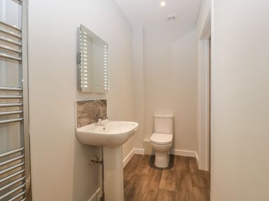 A bathroom with a toilet a sink a mirror with lights and a towel radiator at Dirdale in Weymouth