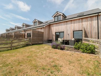 A row of wooden townhouses with small fenced yards and garden furniture at Dirdale in Weymouth