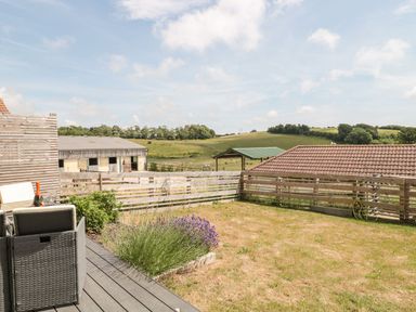 A garden with a wooden fence chairs and a table with a bottle and glasses in Dirdale Weymouth