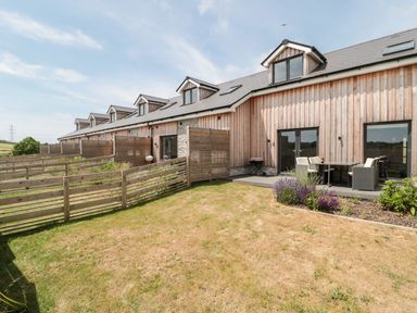 A row of wooden houses with fenced yards and outdoor seating areas at Dirdale in Weymouth