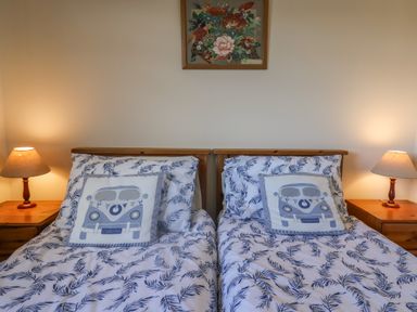 A bedroom with two single beds two bedside tables with lamps and a framed picture on the wall at Broadstones in Bridport