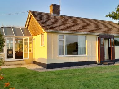 A single story house with a tiled roof and a glass porch at Broadstones in Bridport