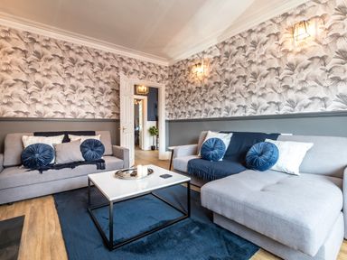 A living room with two grey sofas blue cushions and a white coffee table at Anchor House in Weymouth
