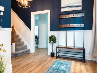 An entryway with a staircase a coat rack a small potted plant a rug and an open doorway leading to another room at Anchor House in Weymouth
