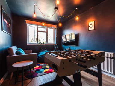 A game room with a foosball table armchair small round table bean bags and a wall-mounted television at Anchor House Weymouth