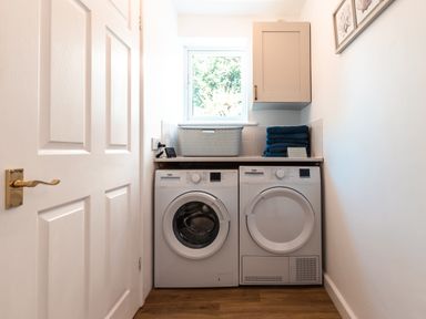 A laundry room with a washing machine dryer stack of towels and a cabinet at Anchor House in Weymouth