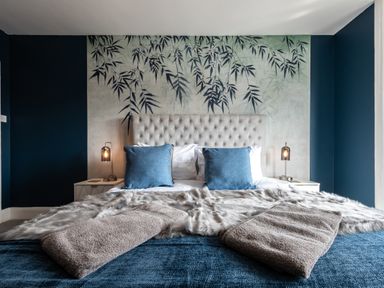A bedroom with a bed with blue pillows and beige towels placed on it at Anchor House in Weymouth