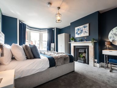 A bedroom with a bed a fireplace a wardrobe and a dressing table at Anchor House in Weymouth