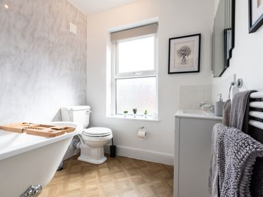 A bathroom with a bathtub toilet sink window and towels at Anchor House in Weymouth
