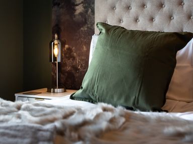 A bed with a green pillow and a bedside table with a lamp at Anchor House in Weymouth