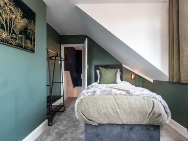 A bedroom with a single bed under a sloped ceiling and green walls at Anchor House in Weymouth