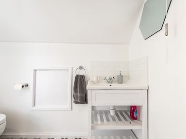 A bathroom with a white sink cabinet gray towel and soap dispenser at Anchor House in Weymouth