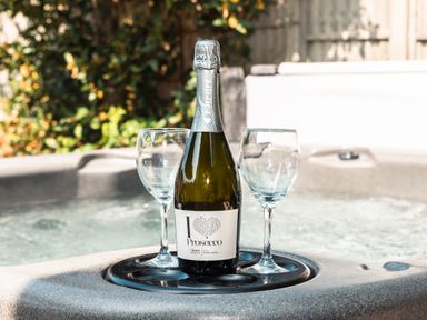 A bottle of prosecco with two wine glasses on a holder in a hot tub at Anchor House in Weymouth