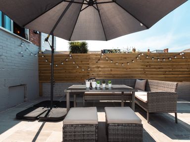 A patio with a table and chairs under a large umbrella at Anchor House in Weymouth