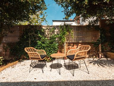 An outdoor patio area with two wicker chairs and a small round table on gravel at Anchor House in Weymouth