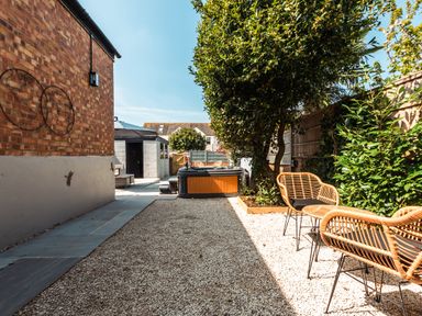 An outdoor patio area with chairs a hot tub and plants at Anchor House in Weymouth