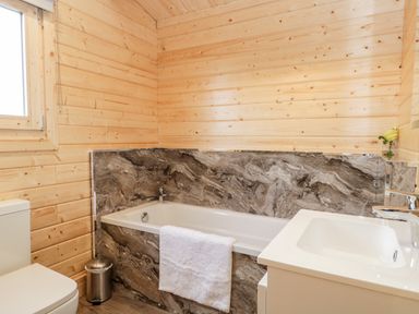 A bathroom with a bathtub a sink a toilet and wooden walls at Howgills Retreat Gatebeck near Kirkby Lonsdale