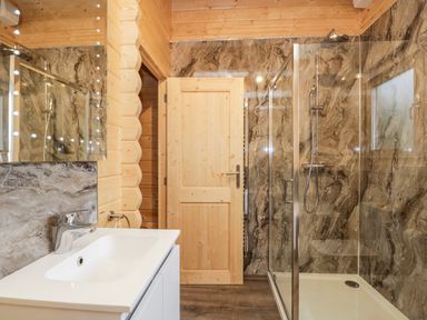 A bathroom with a sink countertop a mirror a wooden door and a glass shower enclosure at Howgills Retreat in Gatebeck near Kirkby Lonsdale