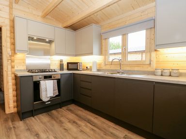A kitchen with a stove oven microwave sink and window at Howgills Retreat Gatebeck near Kirkby Lonsdale