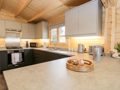A kitchen with wooden ceiling cabinets countertops a sink oven microwave and small appliances at Howgills Retreat Gatebeck near Kirkby Lonsdale