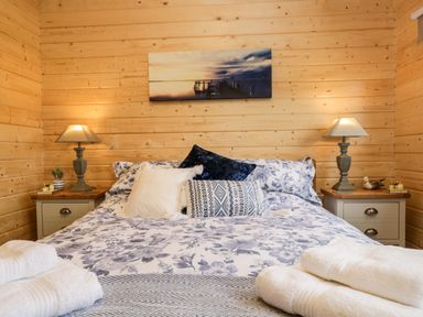 A bed with patterned pillows and lamps on bedside tables in a wooden room at Howgills Retreat in Gatebeck near Kirkby Lonsdale