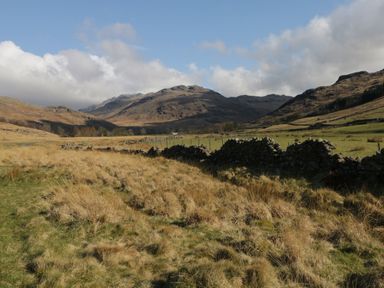 A grassy field with a stone wall and mountains in the background at Howgills Retreat in Gatebeck near Kirkby Lonsdale