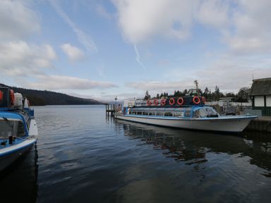 A boat named Miss Cumbria II docked on a lake with a pier and buildings in the background at Howgills Retreat in Gatebeck near Kirkby Lonsdale