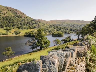 A stone wall with trees and a lake in a valley at Howgill Lodge in Gatebeck near Kirkby Lonsdale