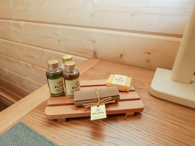 Bottles of shampoo and bath products with soap and a shower cap on a wooden tray on a table at Howgill Lodge in Gatebeck near Kirkby Lonsdale
